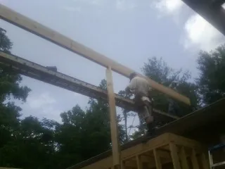 Carpenter setting a ridge beam over a new addition frame — Ice Dam Removal by Roofing Brothers in Brinnon