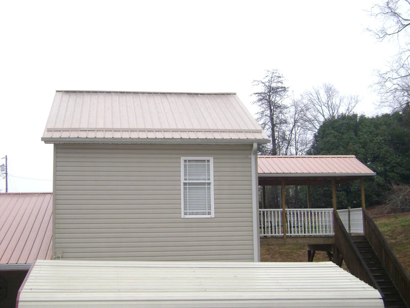 Tan metal roofs on a two story addition and attached porch, from a Roof Replacement job in Brinnon
