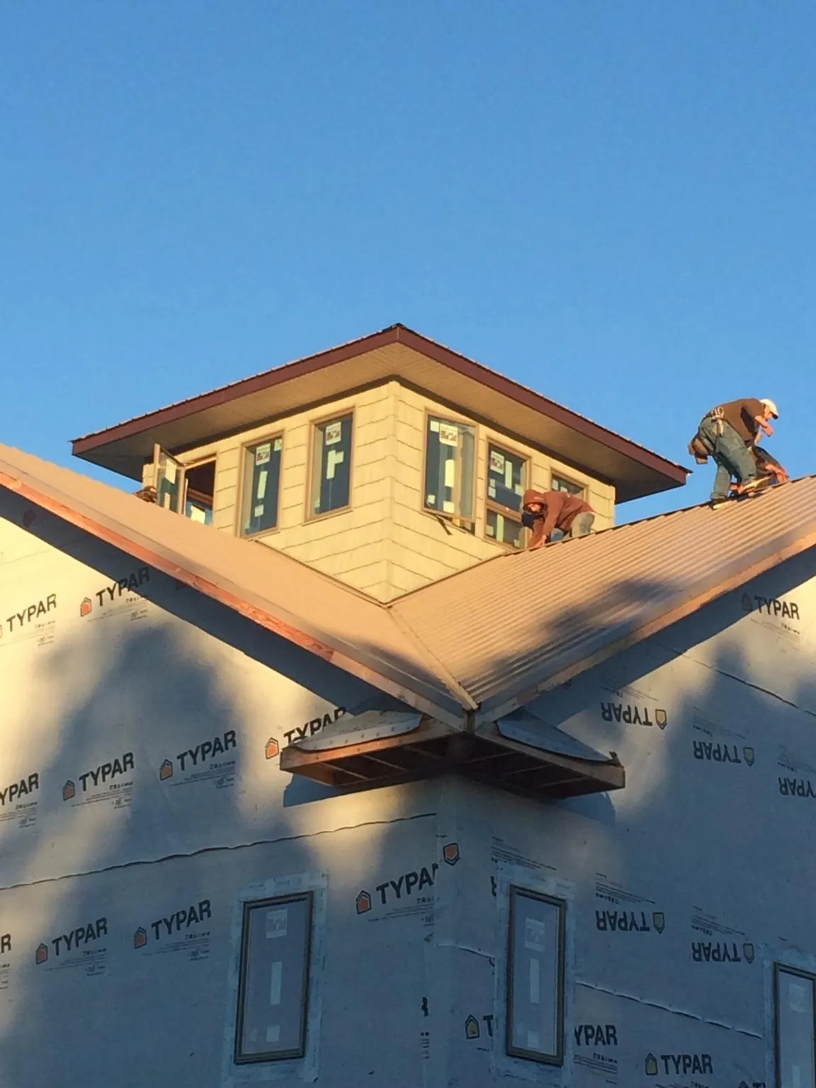 Roofers working around a rooftop cupola on a new metal roof at sunset — Roof Waterproofing in Brinnon by Roofing Brothers